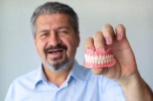 An Adult Male Holding Dentures & Partials in Kokomo Family Dentistry